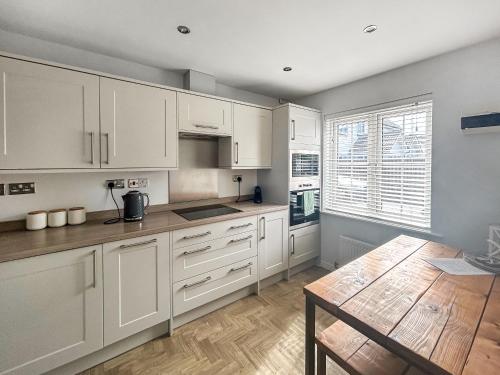 une cuisine avec des armoires blanches et une table en bois dans l'établissement Dory, à Camber