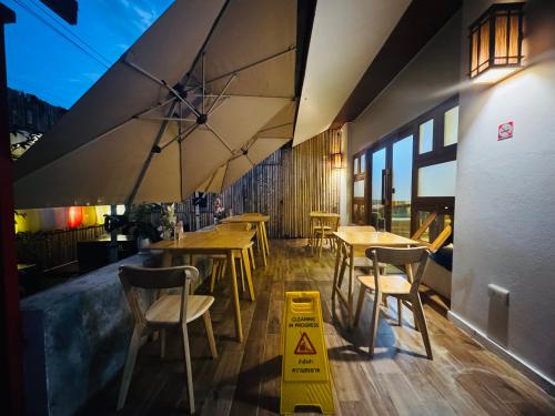 un ristorante con tavoli e sedie in legno e un cartello di avvertenza di Nozawa Hostel and Onsen - Men Only a Chiang Mai