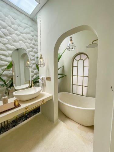Un baño con bañera, lavabo y espejo. en Staycationku Premium Jogja Villas, en Beran-kidul