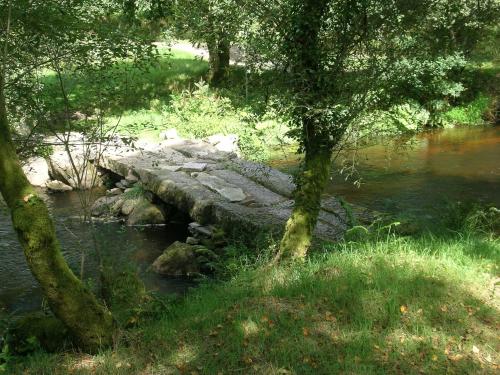 a bridge over a river with trees and grass at Ti Gwen in Plonévez-du-Faou