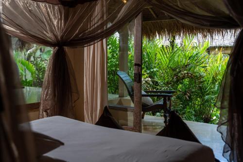 a bedroom with a bed and a chair on a porch at Nomadic Resort Bali in Canggu