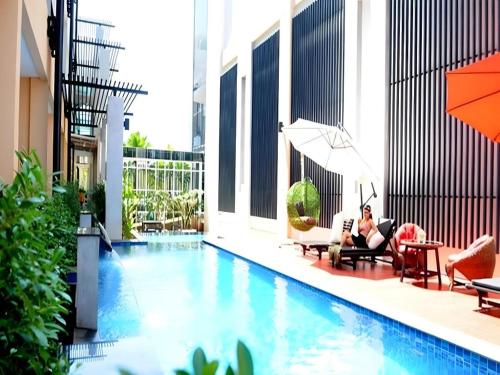 a woman sitting in chairs next to a swimming pool at The O Valley Hotel in Ban Tha Phala Nua