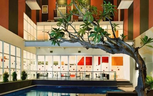 a tree in front of a building with a pool at Amaris Hotel Kupang in Klapalima