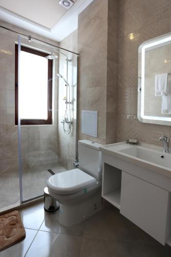 a white bathroom with a toilet and a sink at Hotel Green Garden in Shumen