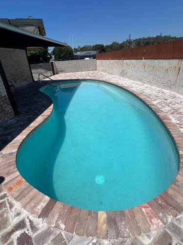 a large blue swimming pool on a brick patio at Cessnock Vintage motor inn in Cessnock