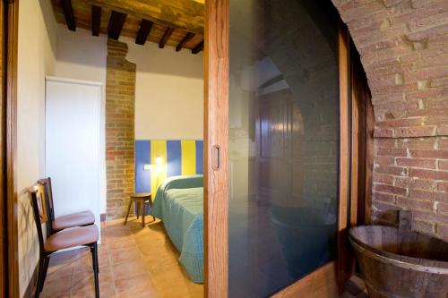 a bedroom with a bed and a room with a chair at Casa vacanza vicolo degli orti in Monticiano