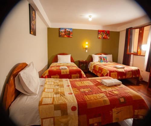 Habitación de hotel con 2 camas y mantas coloridas en El Chasqui, en Ollantaytambo