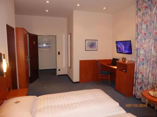 a hotel room with a bed and a desk at Astoria Hotel in Ratingen