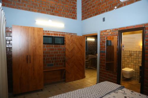 a bathroom with a brick wall and wooden cabinets at The Loft -Aadhya Homestay Hampi in Munirābād