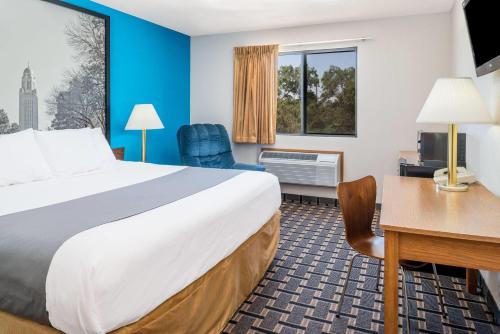 a hotel room with a large bed and a desk at Super 8 by Wyndham Lincoln West in Lincoln