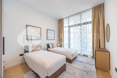 a bedroom with two beds and a large window at Bloomfields Executive 2BR Apt The Gate Masdar in Abu Dhabi