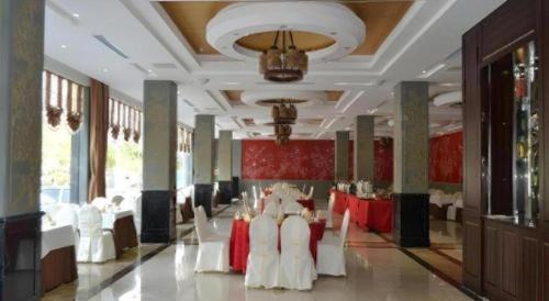 a banquet hall with white chairs and red tables at GreenTree Eastern Yantai Development Zone Zhujiang Road Hotel in Yantai