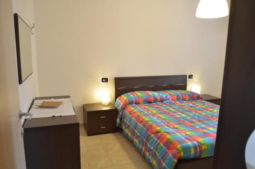 una camera da letto con un letto con un piumone colorato e una scrivania di La Perla del Magra Holidays House a Monte Marcello
