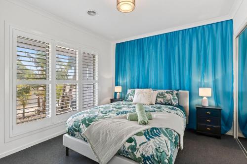 een slaapkamer met blauwe gordijnen, een bed en een raam bij Palms by the sea in Saint Leonards