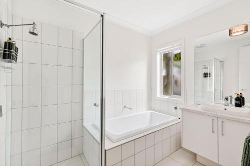 een witte badkamer met een bad en een wastafel bij Palms by the sea in Saint Leonards