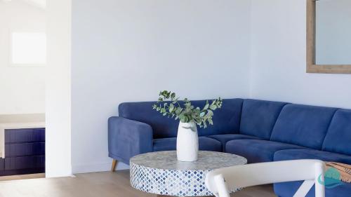 een blauwe bank met een tafel met een vaas erop bij Oceanview Beach House in Caves Beach