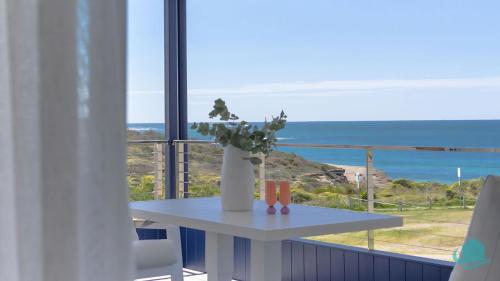 een tafel met een plant op een balkon met uitzicht op de oceaan bij Oceanview Beach House in Caves Beach