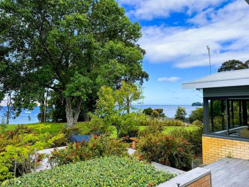 a garden in front of a house with the ocean in the background at wyeangta - Woodbridge Waterfront Retreat in Woodbridge