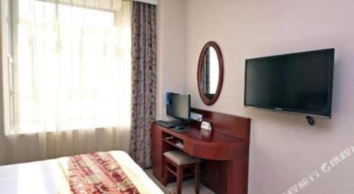 a hotel room with a bed and a desk with a television at GreenTree Inn Shanghai Jiading Newtown MaLu Subway Station Business Hotel in Jiading