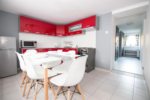 a kitchen with red cabinets and a white table and chairs at Apartament Zacisze Tatr in Zakopane