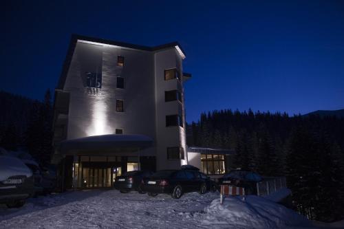 a building with two cars parked in front of it at night at Hotel FIS Jasná in Demanovska Dolina