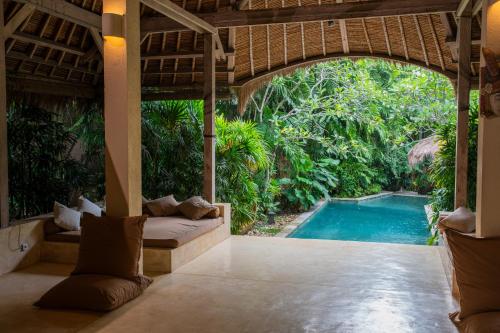 an outdoor living room with a pool and a resort at Nomadic Resort Bali in Canggu