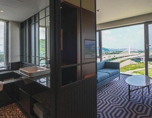Una habitación de hotel con un sofá y vistas a un puente. en 호텔 마리나베이 코리아 Hotel Marinabay Korea Ara, en Gimpo