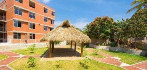 a large straw umbrella in front of a building at Departamento Villas Doradas in Santa Cruz Huatulco