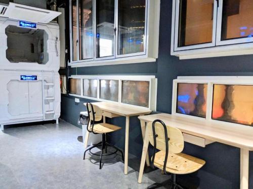 a room with a table and chairs and a wall with windows at MET A Space Pod @ Chinatown in Singapore