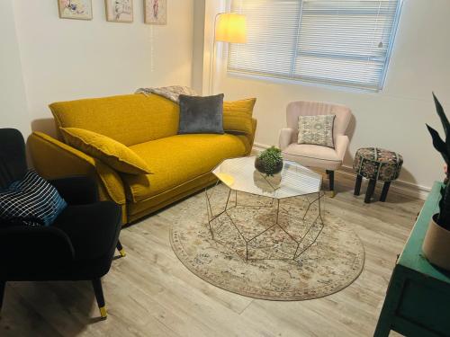 a living room with a yellow couch and a chair at Chic Retreat in Granville - steps to train ! in Clyde
