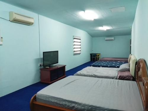 a room with two beds and a flat screen tv at Village House With River View And Karaoke 8 to10 Pax in Jeram
