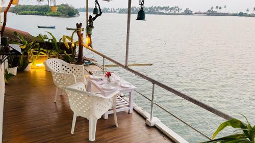 a table and chairs sitting on a deck next to the water at Palm Breeze in Udupi