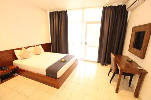 a bedroom with a bed and a table and a window at The Melanesian Port Vila in Port Vila