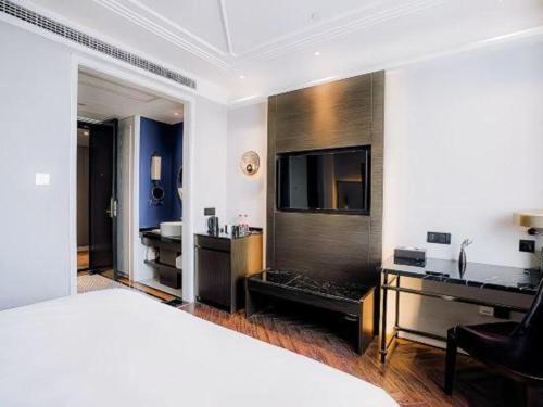 a bedroom with a bed and a desk and a television at Jinjiang Metropolo Hotel Nanjing Jiangning Binjiang Development Zone in Qingxiu