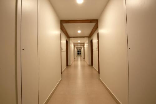 a corridor in a building with white walls and a long hallway at Palguni Residency in Hassan