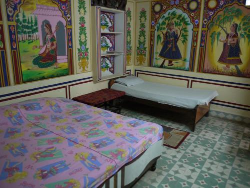 a room with two beds and paintings on the walls at Hotel Shekhawati, A boutique stay in Mandāwa