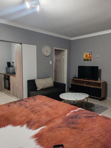 Ekukhanyeni Guest house في Kwaluseni: غرفة معيشة بها سرير وأريكة