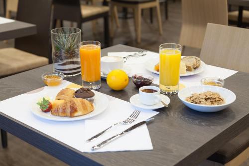 a table with plates of breakfast foods and orange juice at Novotel Brescia Due in Brescia