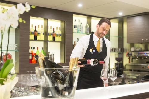 a man pouring a bottle of wine in a bar at Novotel Brescia Due in Brescia