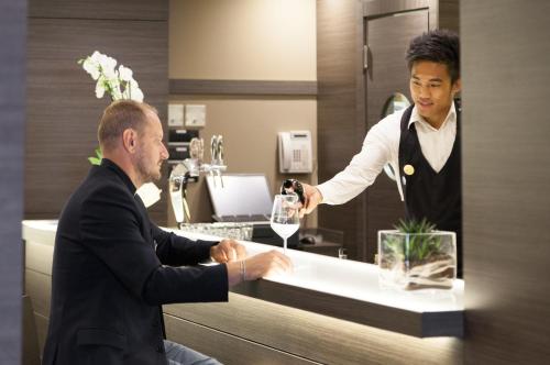 a man getting a glass of wine from a bartender at Novotel Brescia Due in Brescia