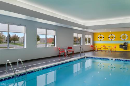 a swimming pool with tables and chairs in a building at Tru By Hilton Battle Creek in Battle Creek