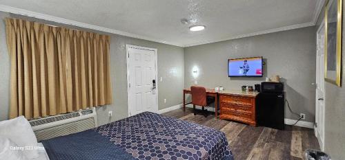 a bedroom with a bed and a desk with a television at Sycamore Inn Chico University Area in Chico