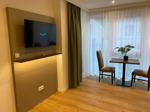 ein Wohnzimmer mit Fernseher und Tisch mit Stühlen in der Unterkunft Living Inn in Rheda-Wiedenbrück
