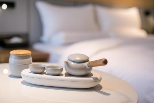 Ein Tablett mit drei Teesets auf einem Tisch neben einem Bett in der Unterkunft JI Hotel Shanghai Xuhui Riverside in Shanghai