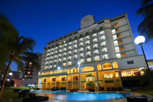 De Greenish Village Langkawi في كواه: مبنى كبير يوجد أمامه حمام سباحة