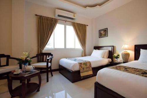 a hotel room with two beds and a chair at Lao Golden Hotel in Ban That-Louang