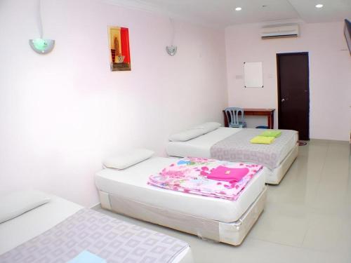 three beds in a room with white walls at Taipann Hotel in Kampong Telok Gadong Besar