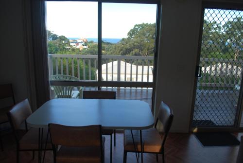 a white table and chairs in a room with a balcony at Lookout Holiday Units in Lakes Entrance