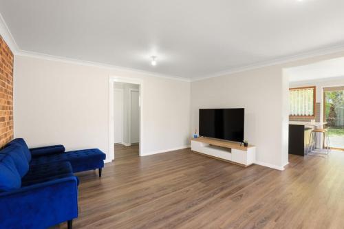 een woonkamer met een blauwe bank en een flatscreen-tv bij Aqua on Achilles in Nelson Bay