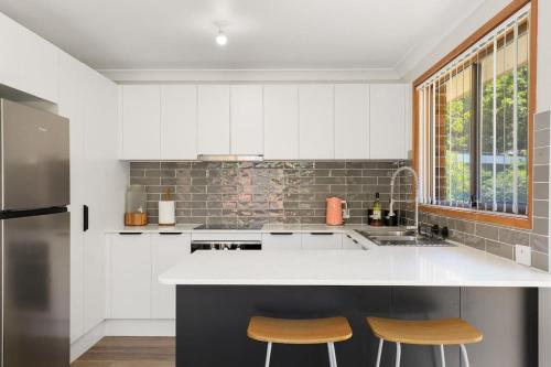 een keuken met een wit aanrecht en 2 krukken bij Aqua on Achilles in Nelson Bay